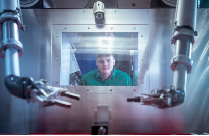 Researcher manoeuvring pair of robotic arms inside a hot cell