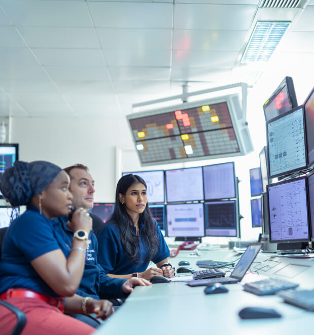 Three tokamak operators view screens in control room